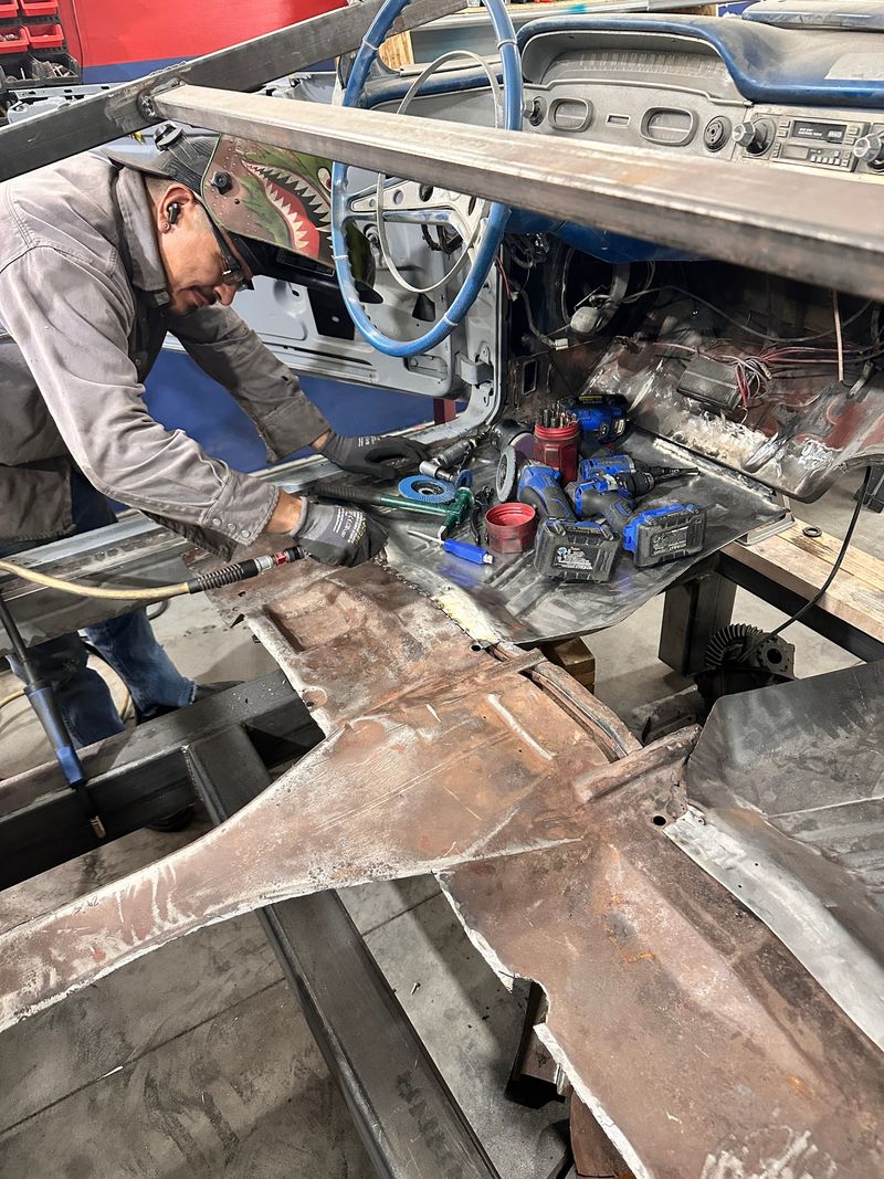 Technician inside the stripped Impala body cutting out the rusted original floor